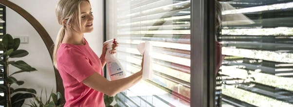 Frau wäscht die großen Fenstertüren mit einem Papierhandtuch und Spray